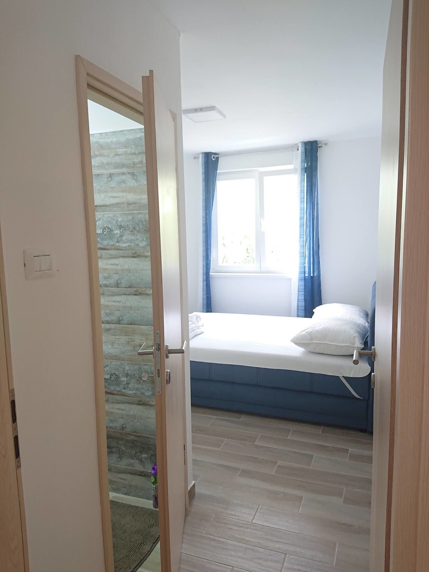 Bedroom with a bed by the window, seen through the doorway