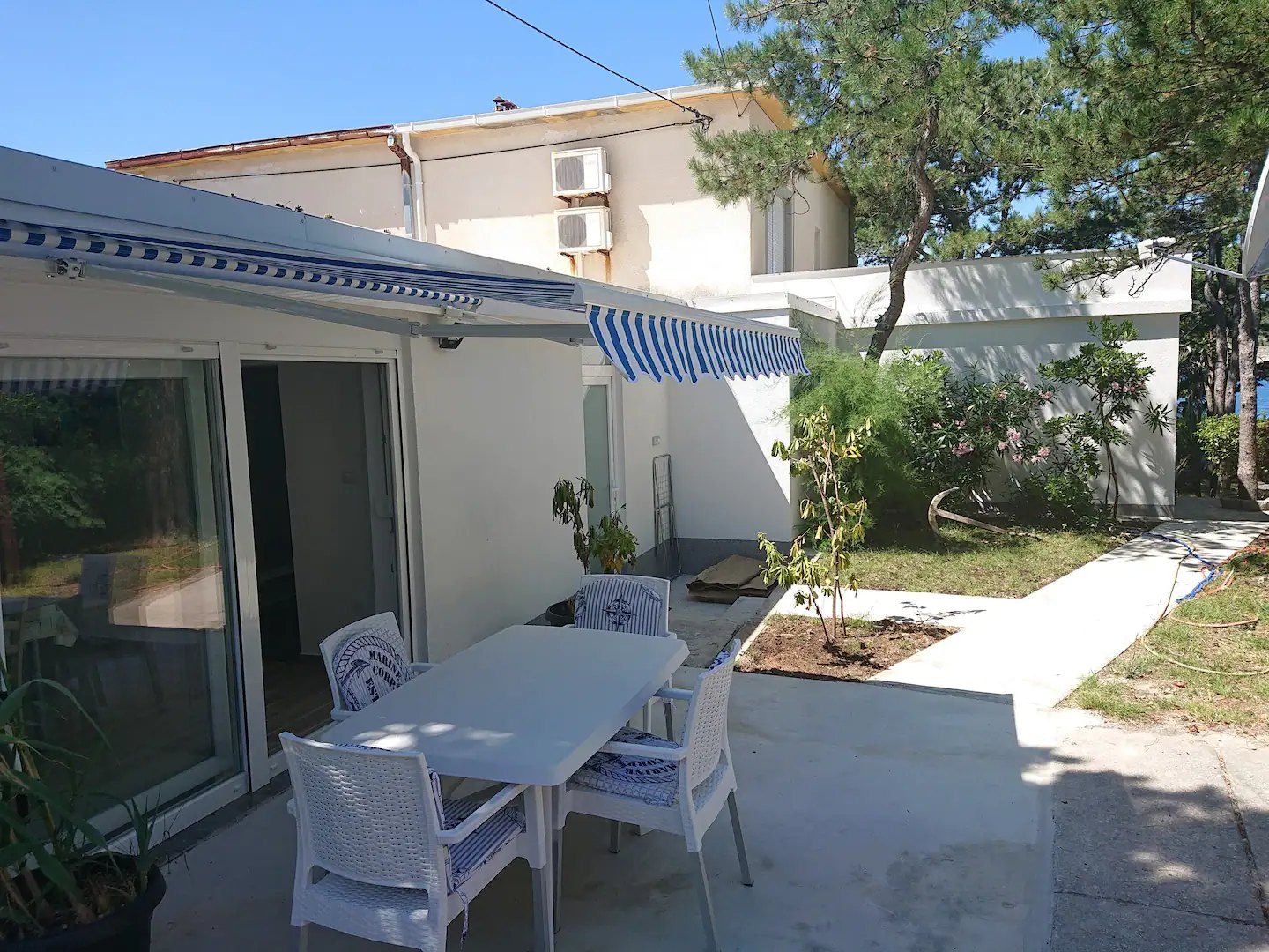 Outdoor dining table and chairs on the terrace, with the garden and the house behind