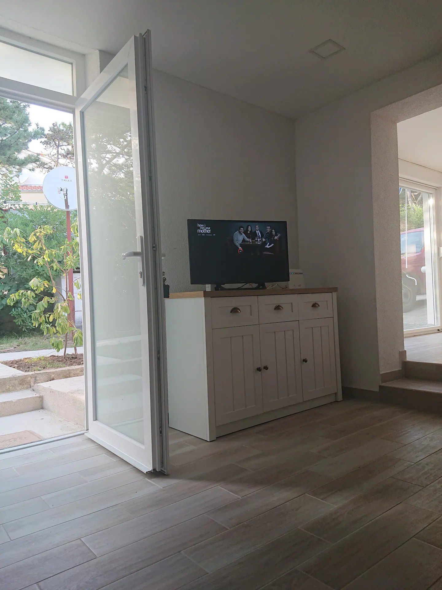 Television cabinet and the open door to the garden
