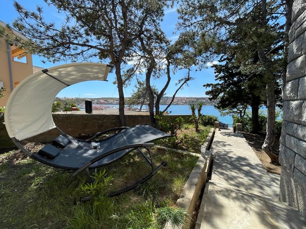 Garden with a hanging lounger under the pines and the sea across the bay