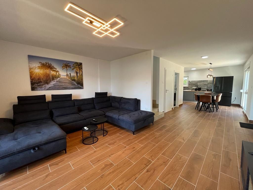 Open living room with a corner sofa and the dining table beyond