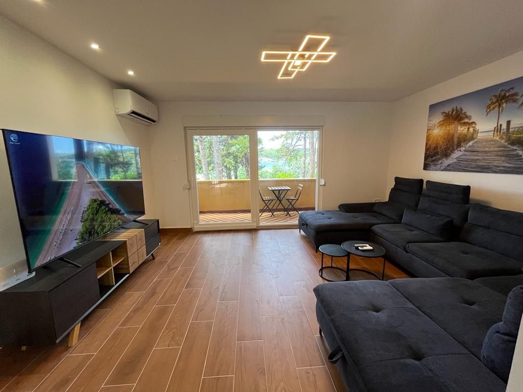 Living room with a large television, corner sofa and doors to the balcony